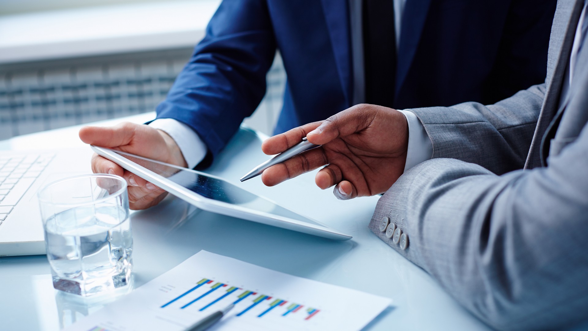 Image of businessmen hands during discussion of data in touchpad at meeting